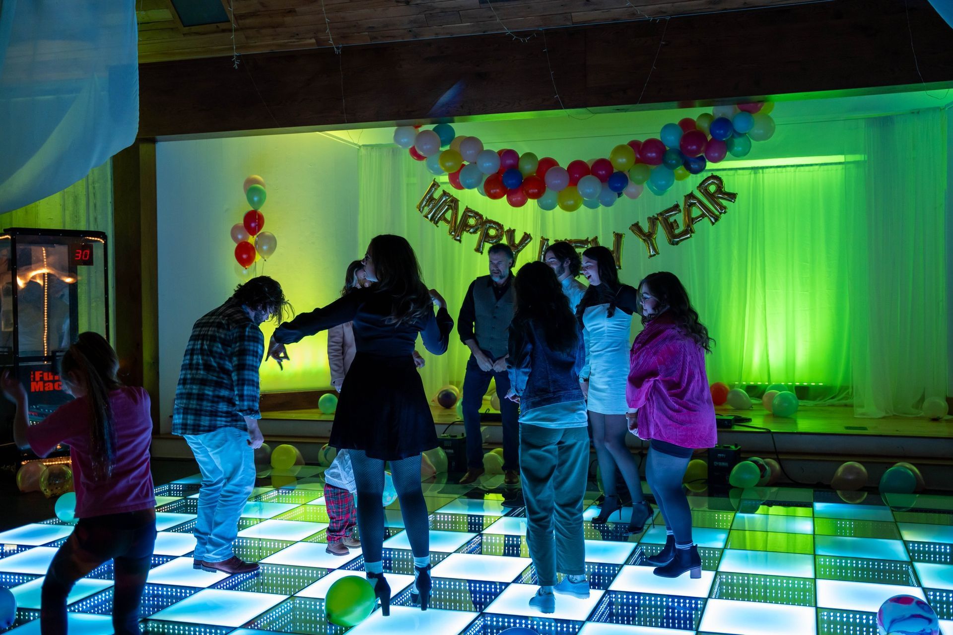 A group of people are dancing in front of a happy new year banner