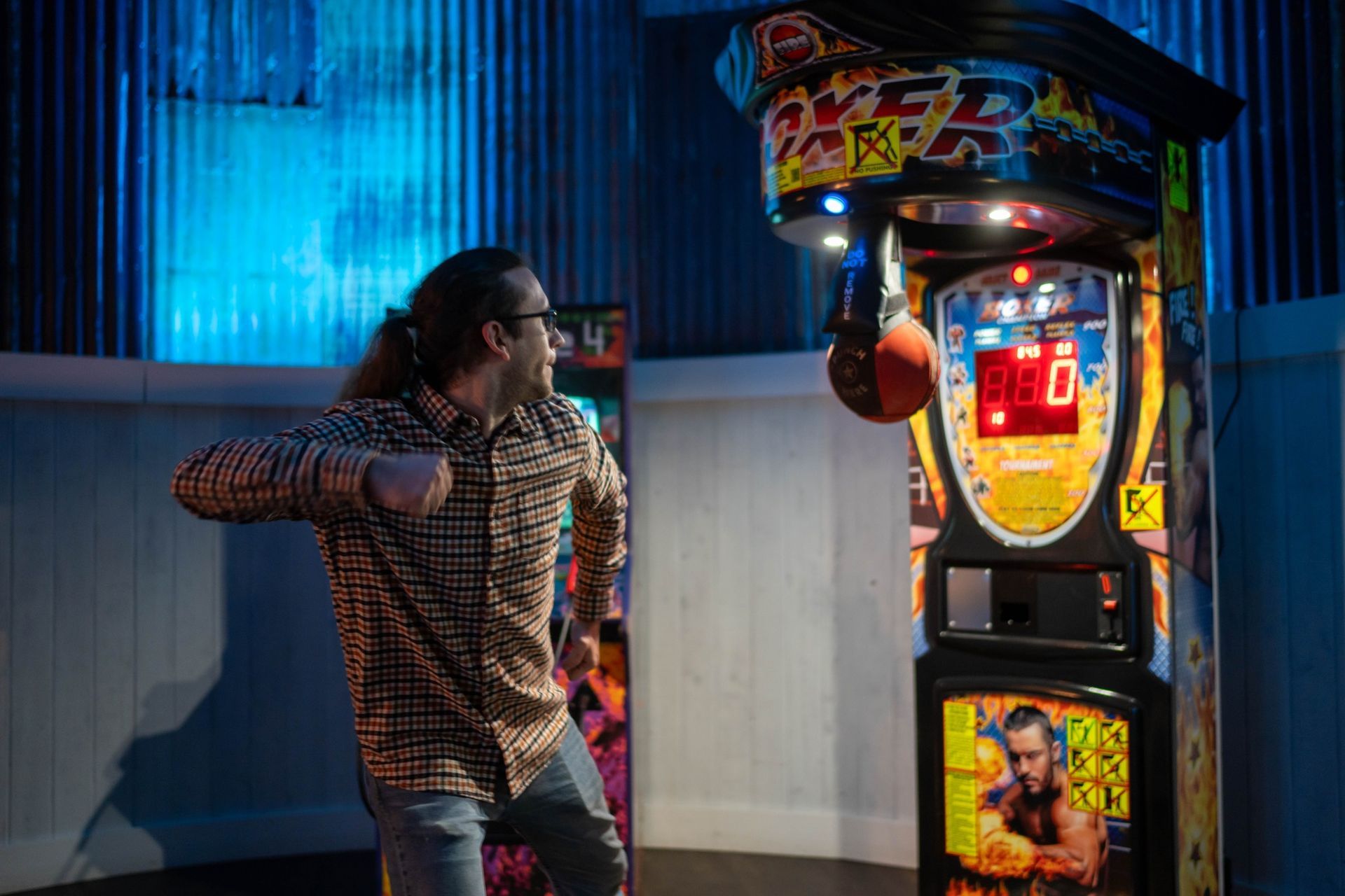 A man is playing a boxing game in an arcade.
