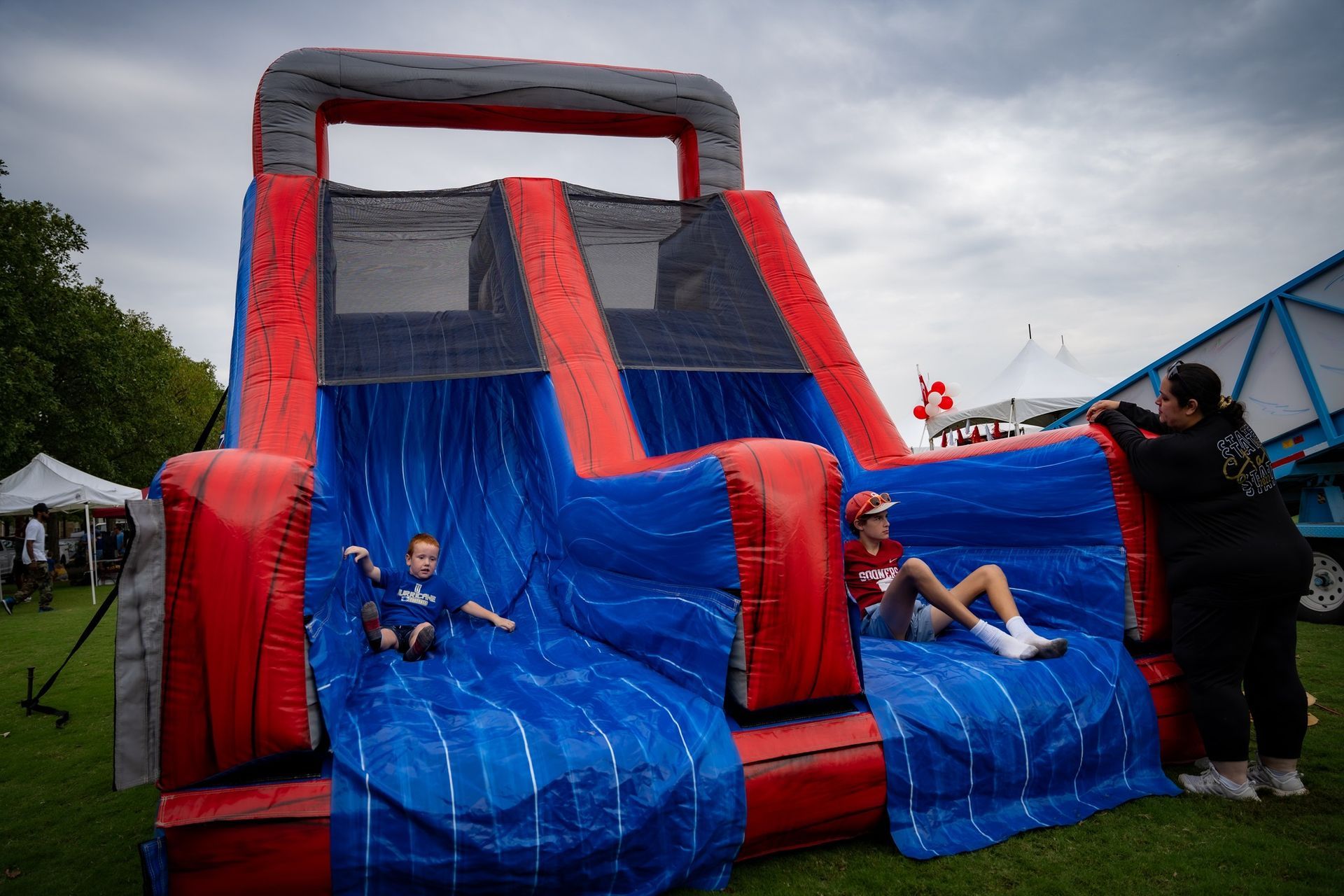 A woman is taking a picture of two children playing on an inflatable slide.