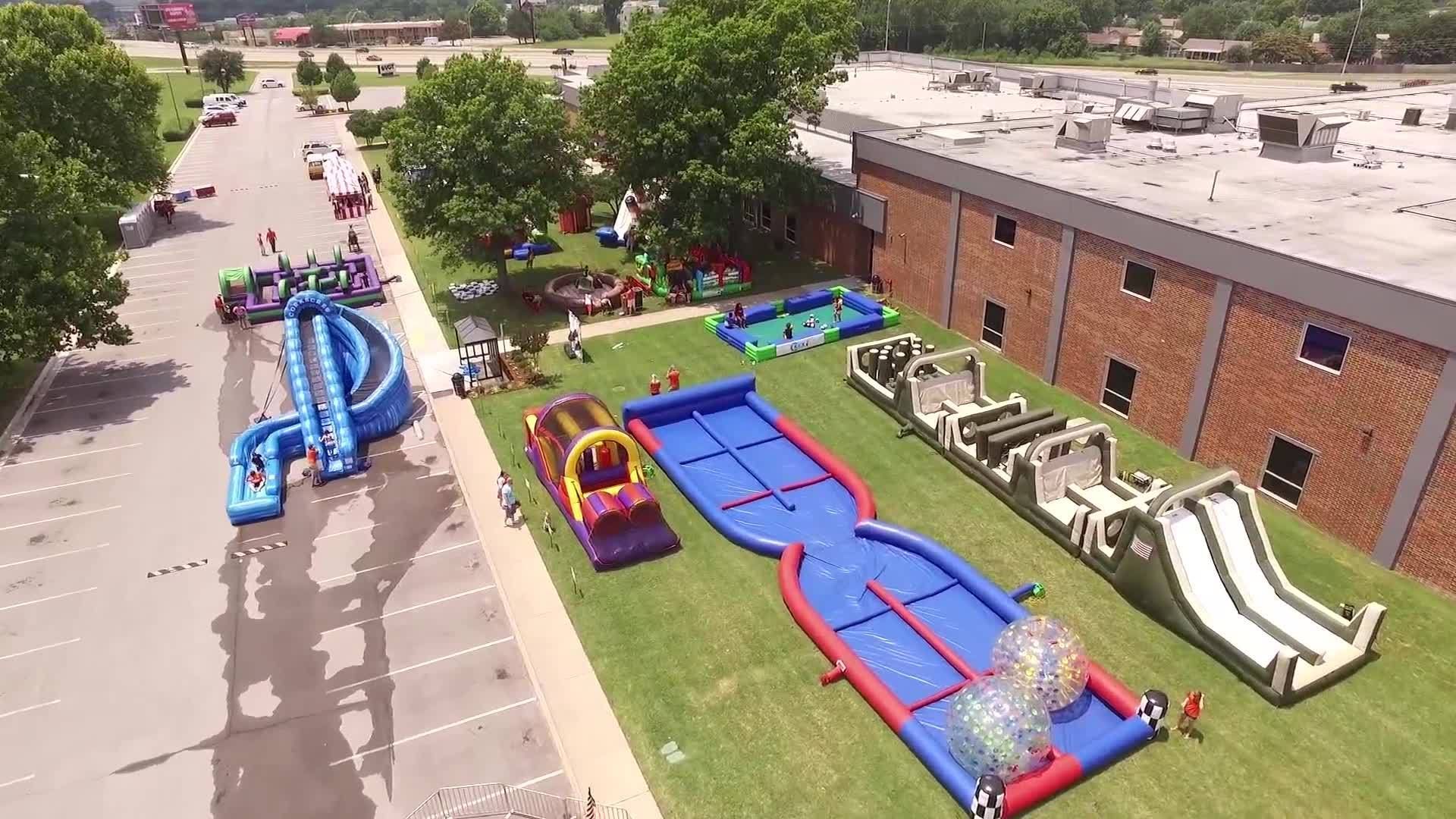 An aerial view of a large inflatable water park in front of a brick building.