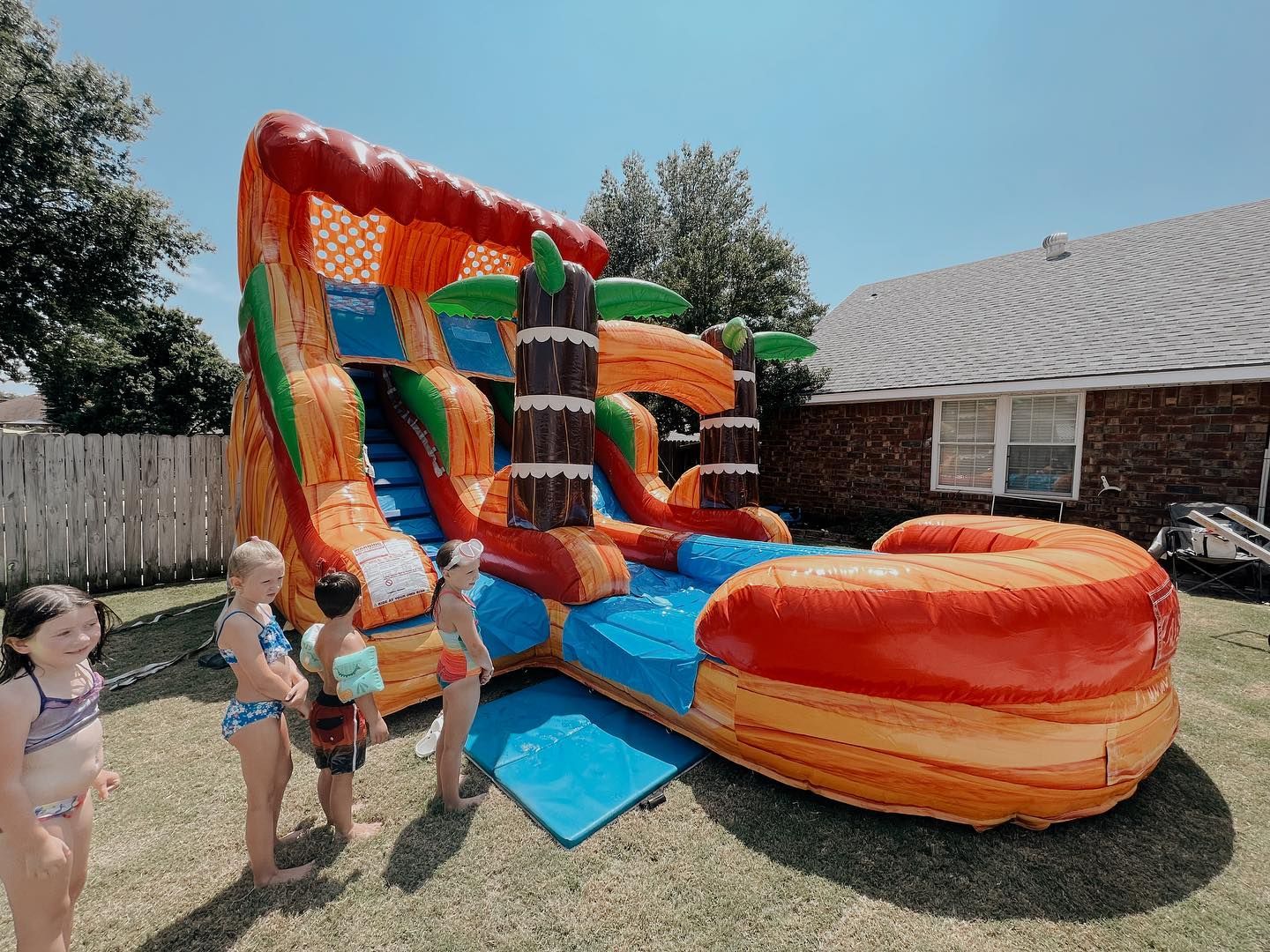 A group of children are standing in front of an inflatable water slide.