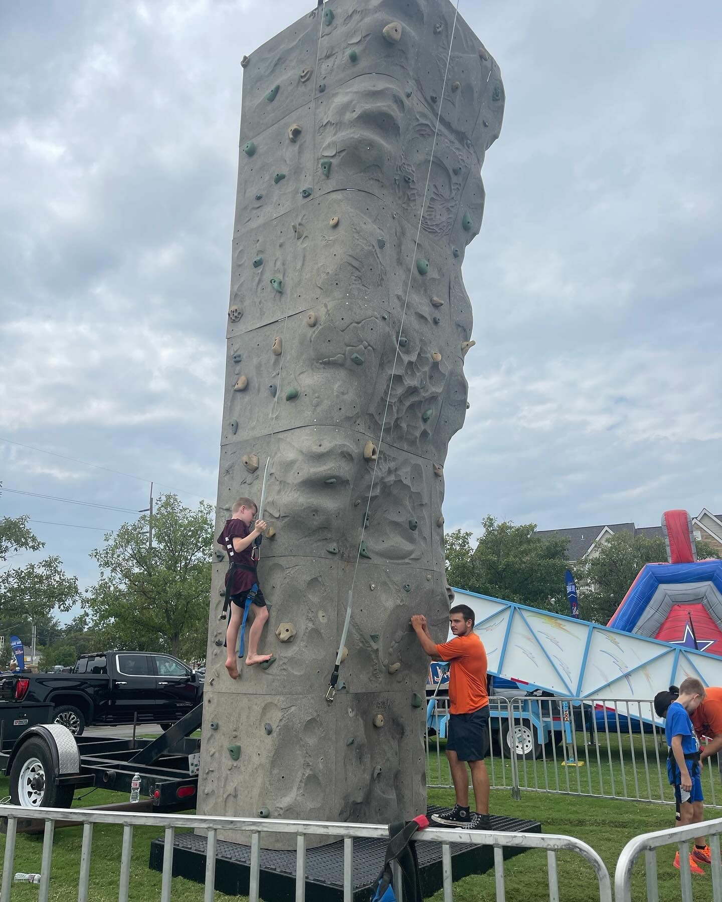 A boy is climbing a climbing wall in a park.