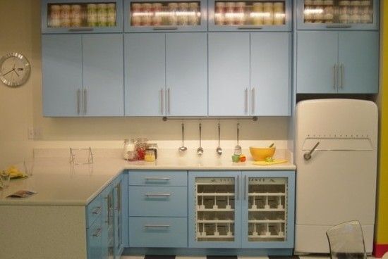 Blue kitchen cabinets with glass-front uppers, white counters, and a retro-style refrigerator.