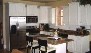 White kitchen with stainless steel appliances, granite countertops, and an island with stools.
