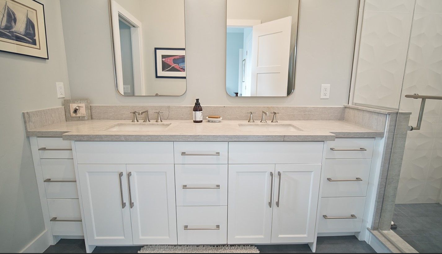 White double-sink bathroom vanity with two mirrors, silver hardware, and light countertop.
