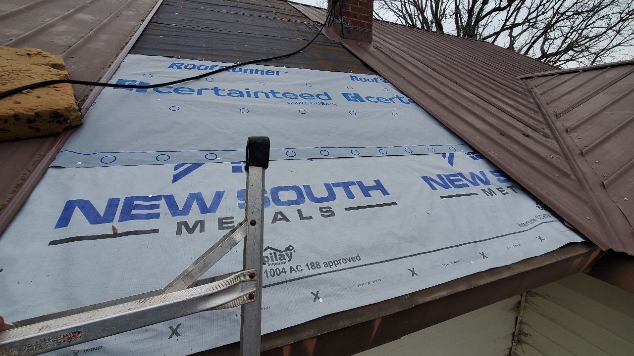 A metal roof repair in progress with a section of underlayment featuring "New South Metals" branding exposed.