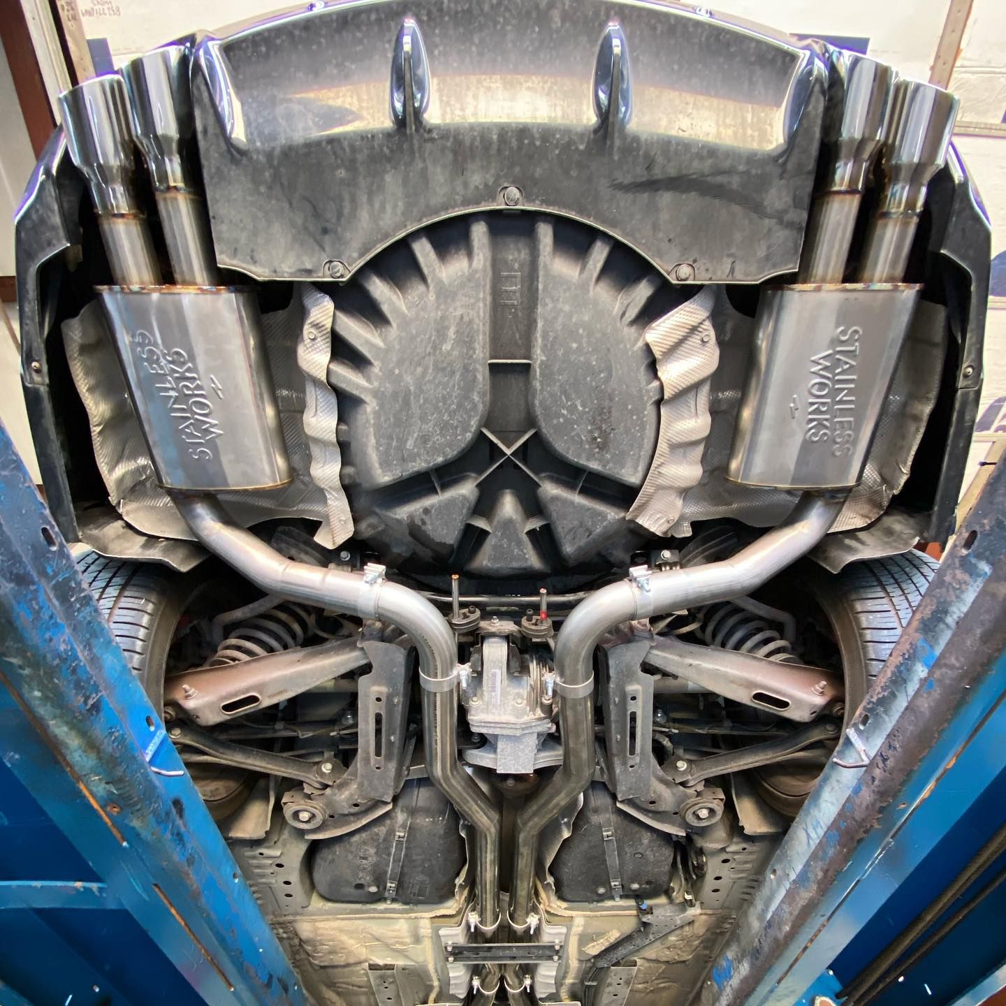Underside view of a car, showing the exhaust system with silver mufflers and pipes.