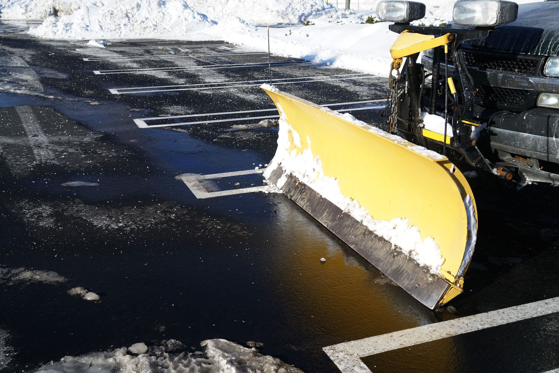 Yellow snowplow clearing a parking space.