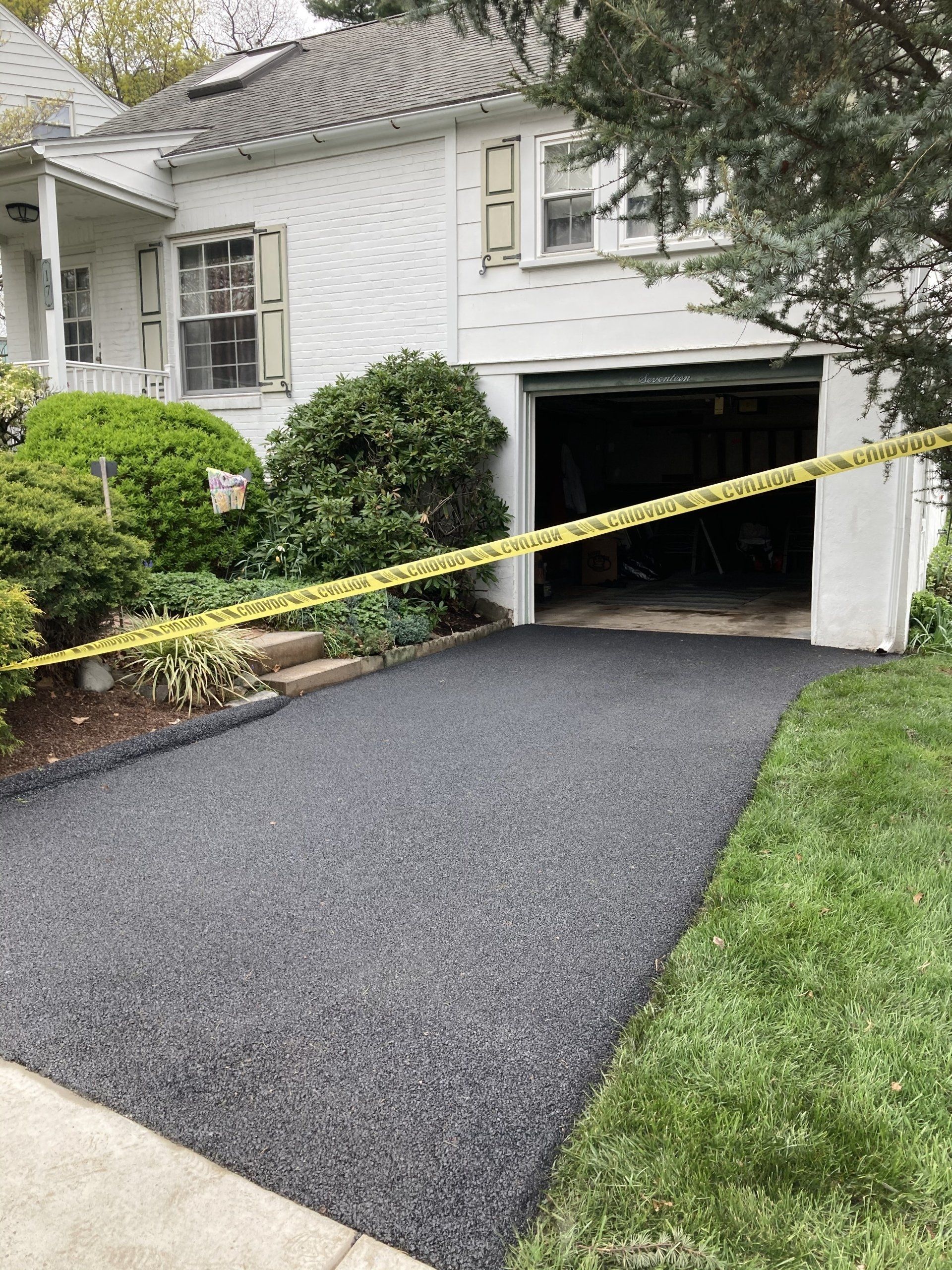 A white house with a black driveway and a garage.