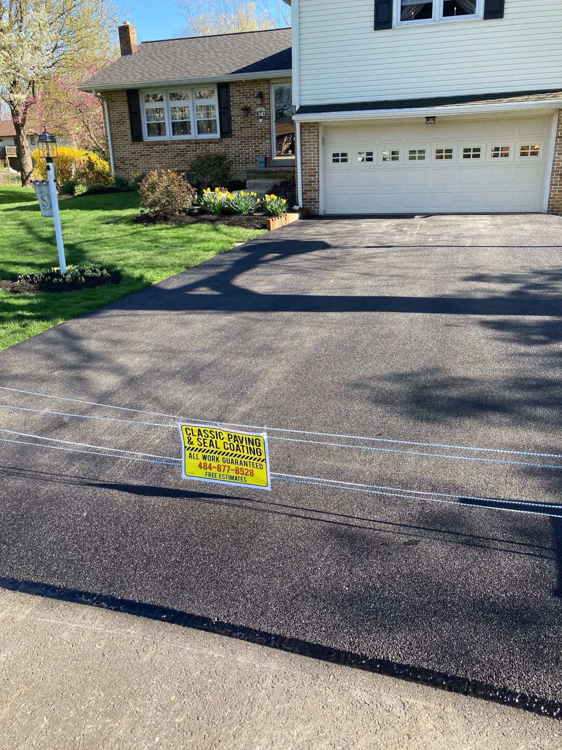 A driveway with a yellow sign on it in front of a house.