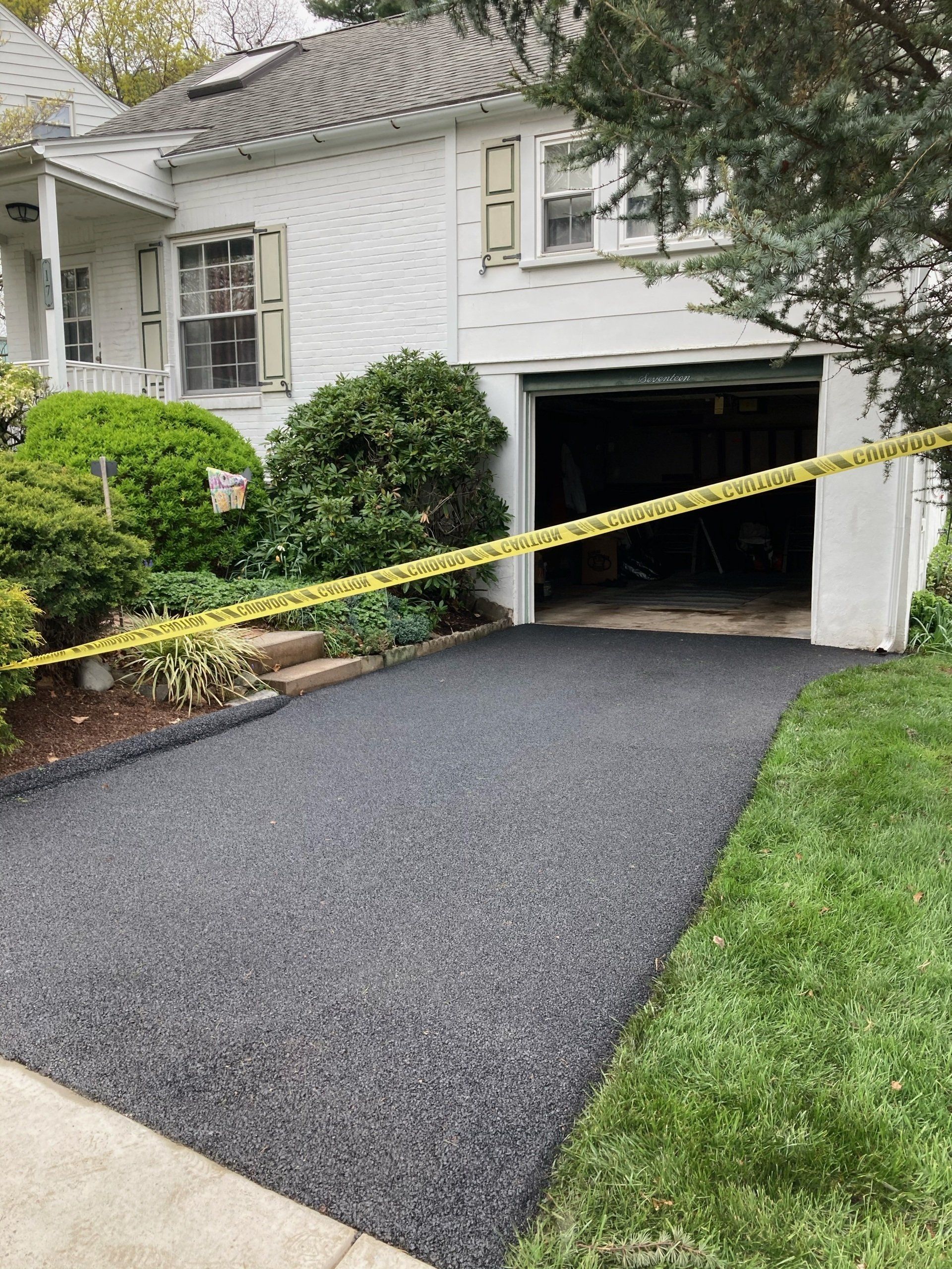 A white house with a black driveway and a garage.