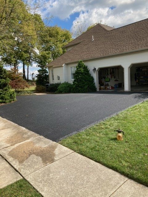 A house with a large driveway and a lawn in front of it.