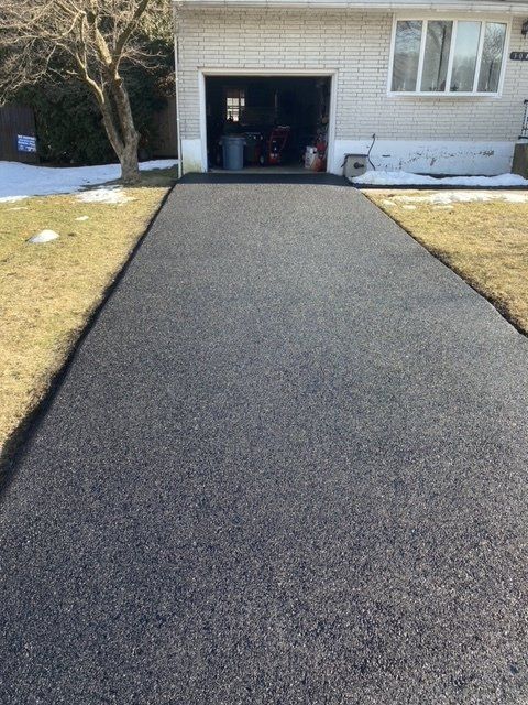 A driveway leading to a house with a garage in the background