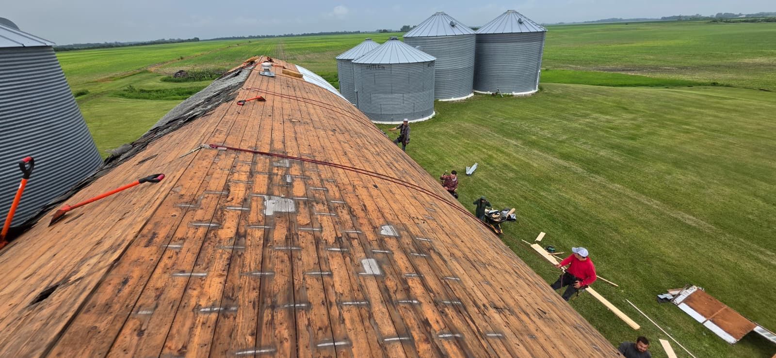 Rusted roof with workers near grain silos in a rural field