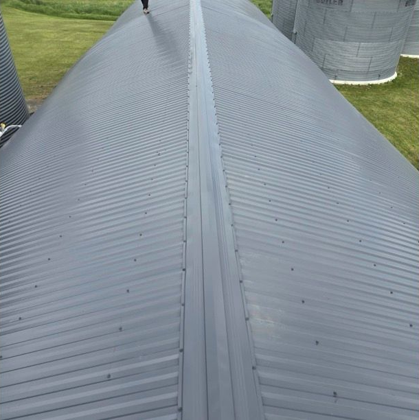 Close-up of a gray corrugated metal roof on a large building, viewed along the ridge line.
