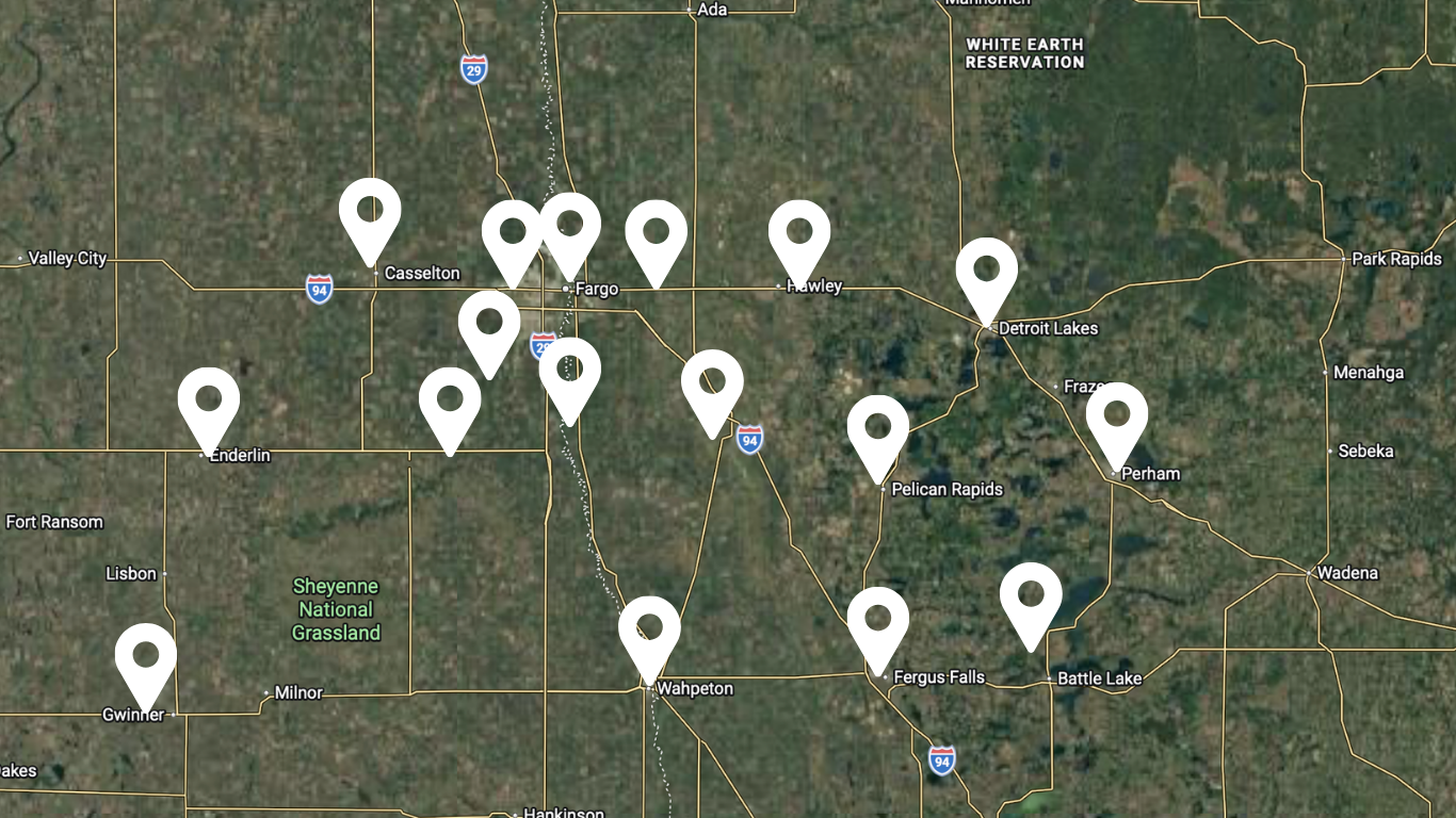 Satellite map with many white location pins marking scattered sites in a rural green landscape