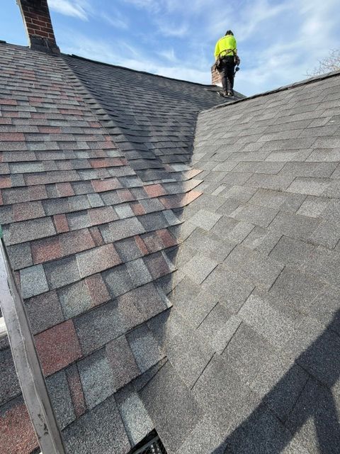 Workers installing black roofing membrane on a flat rooftop with tools and materials nearby.