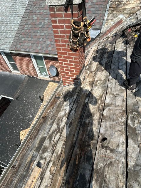 Roofer’s tool bag on a steep wooden roof beside a brick chimney