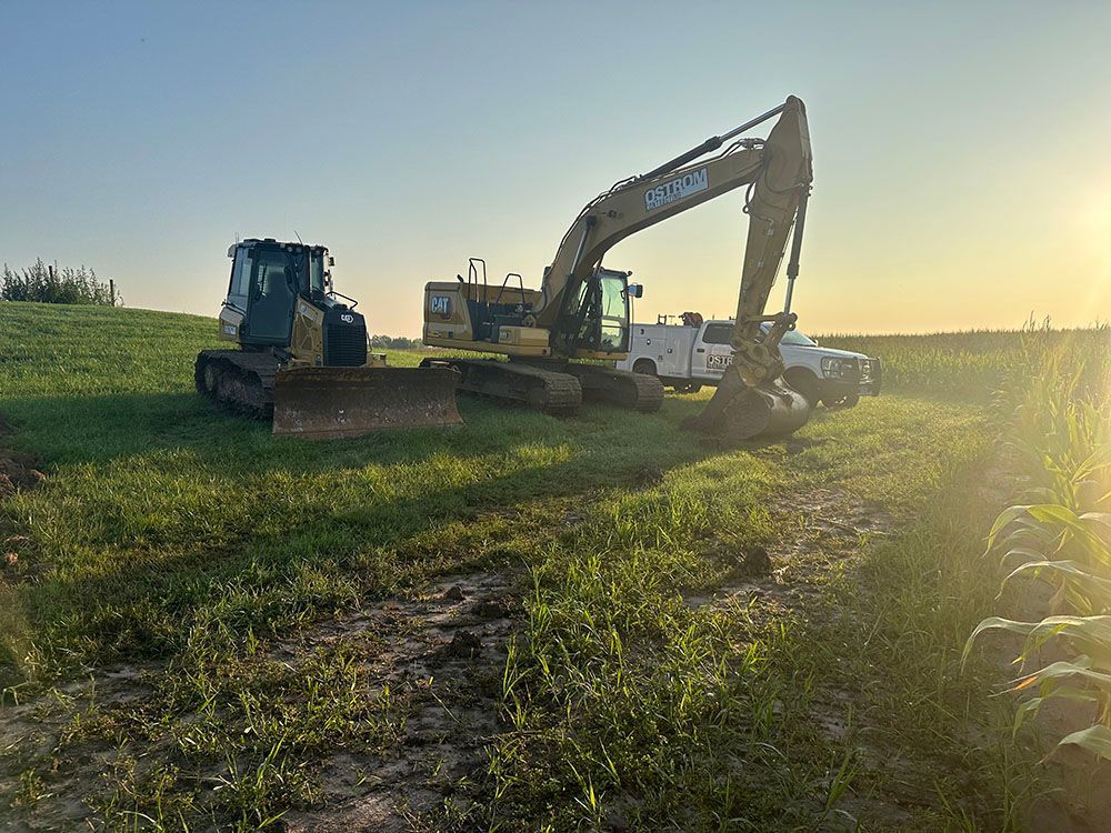 A bulldozer and an excavator are parked in a field.