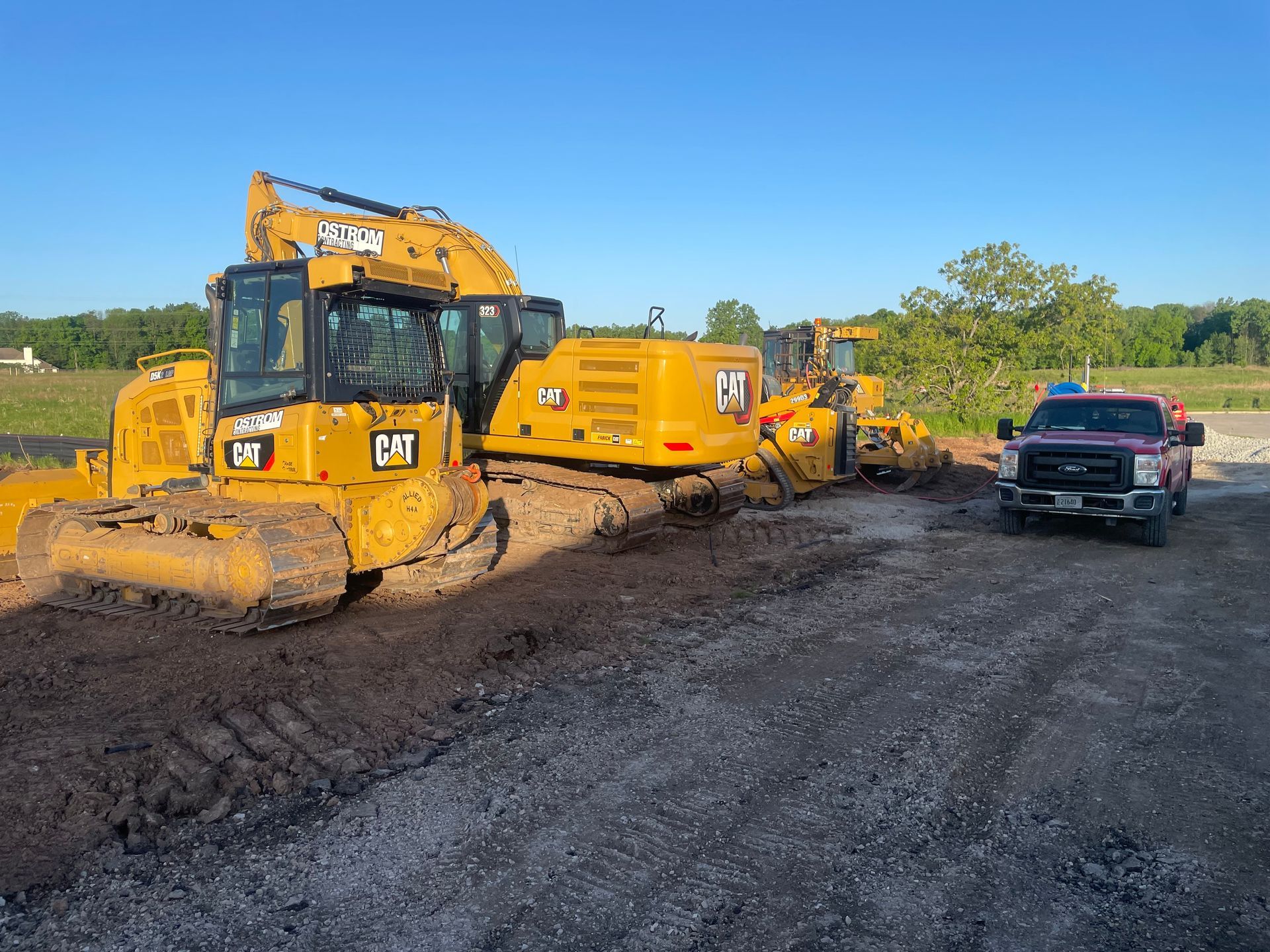 A bulldozer and a truck are parked in a dirt lot.