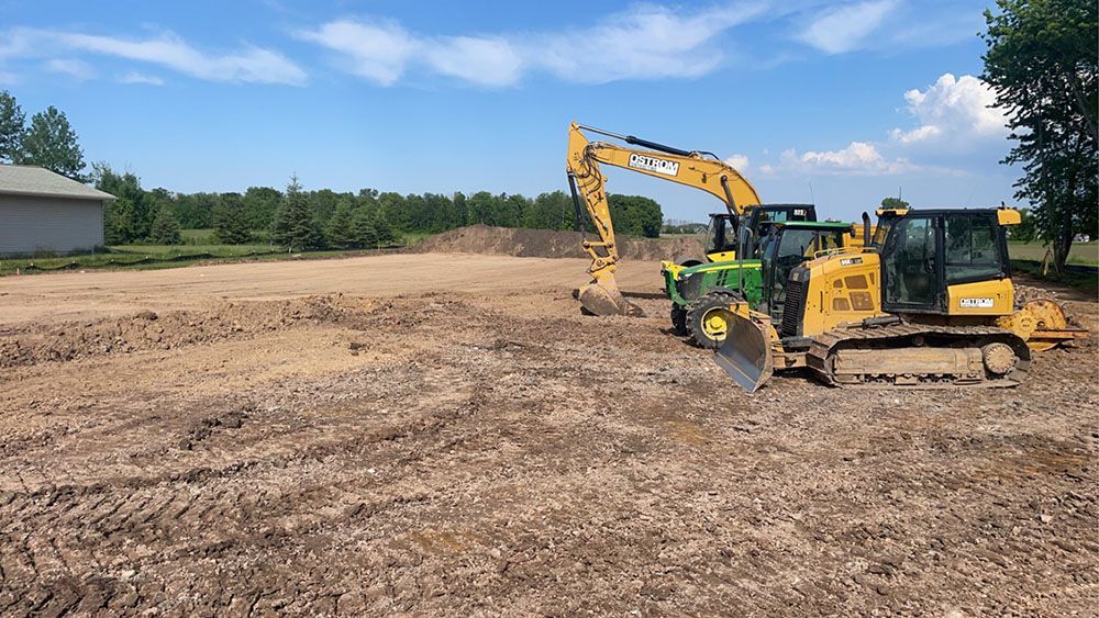 A bulldozer and an excavator are working on a dirt field.