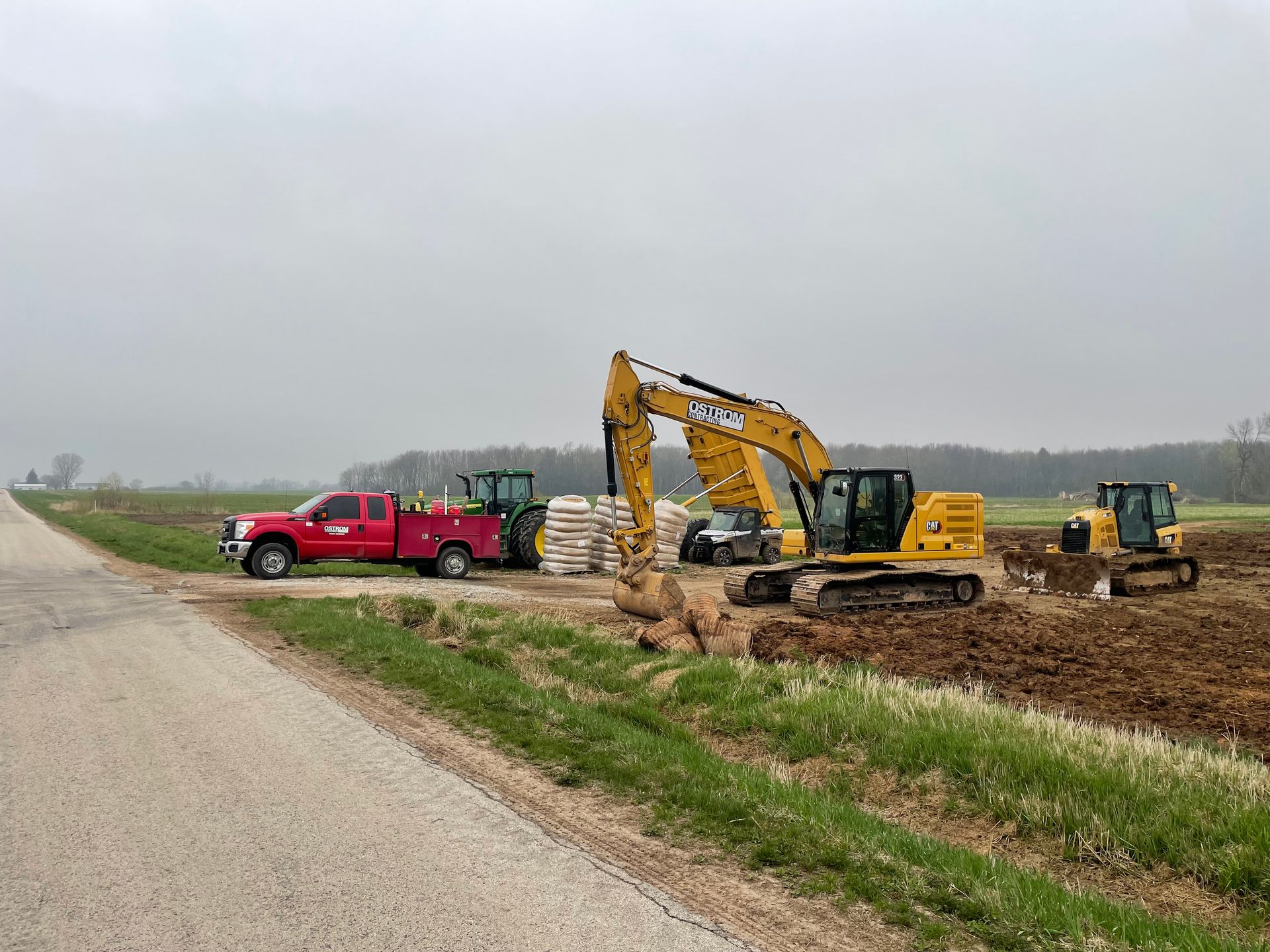 A red truck is parked on the side of the road next to a construction site.