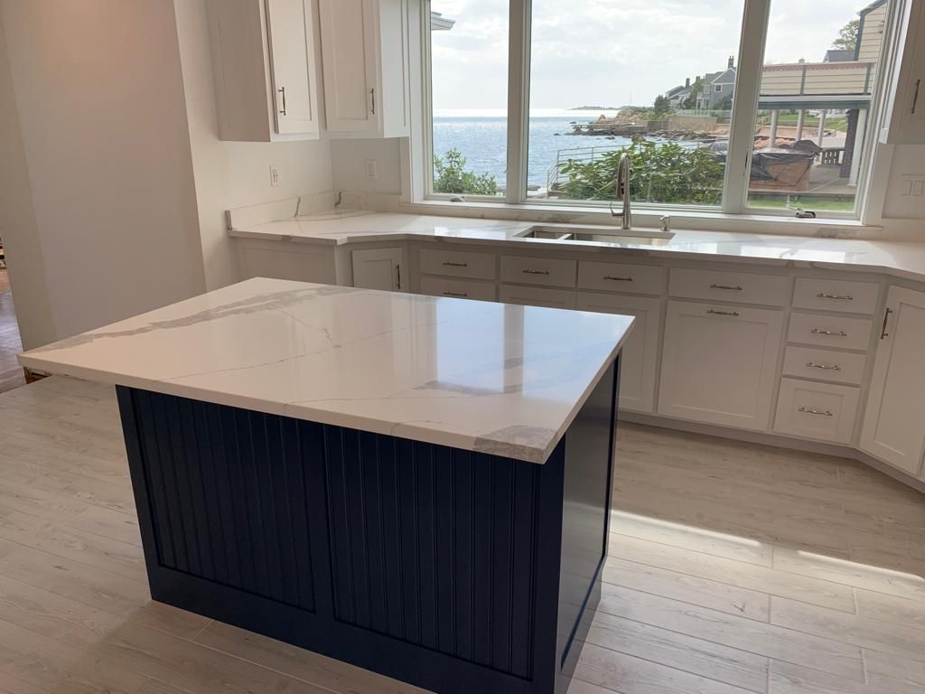 A kitchen with a large island in the middle and a window overlooking the ocean.