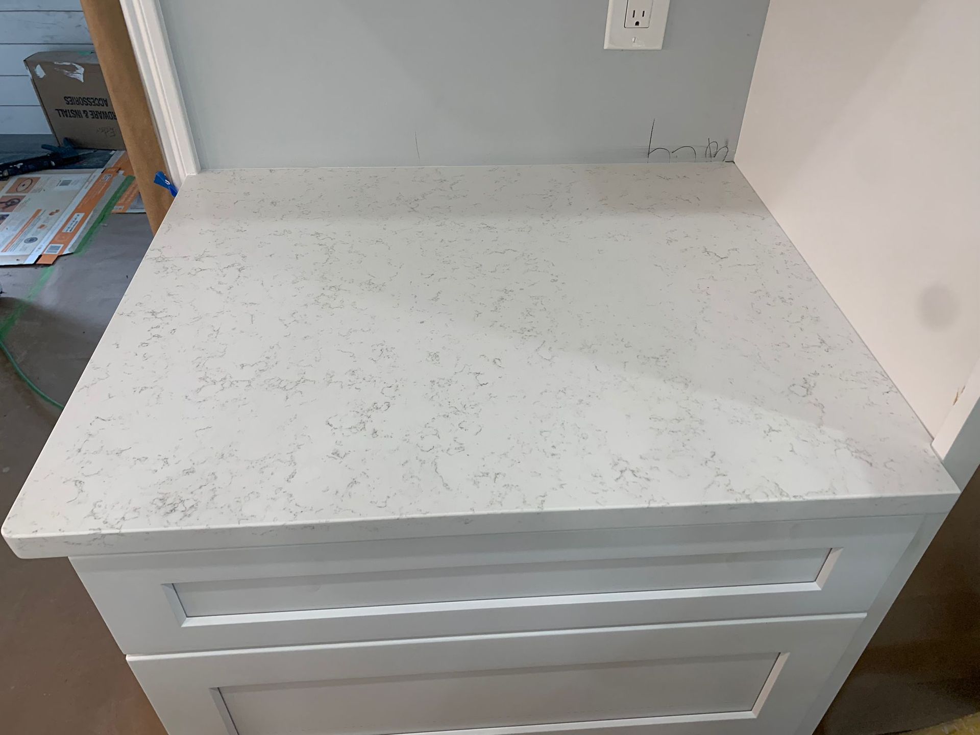 A white counter top is sitting on top of a white cabinet.