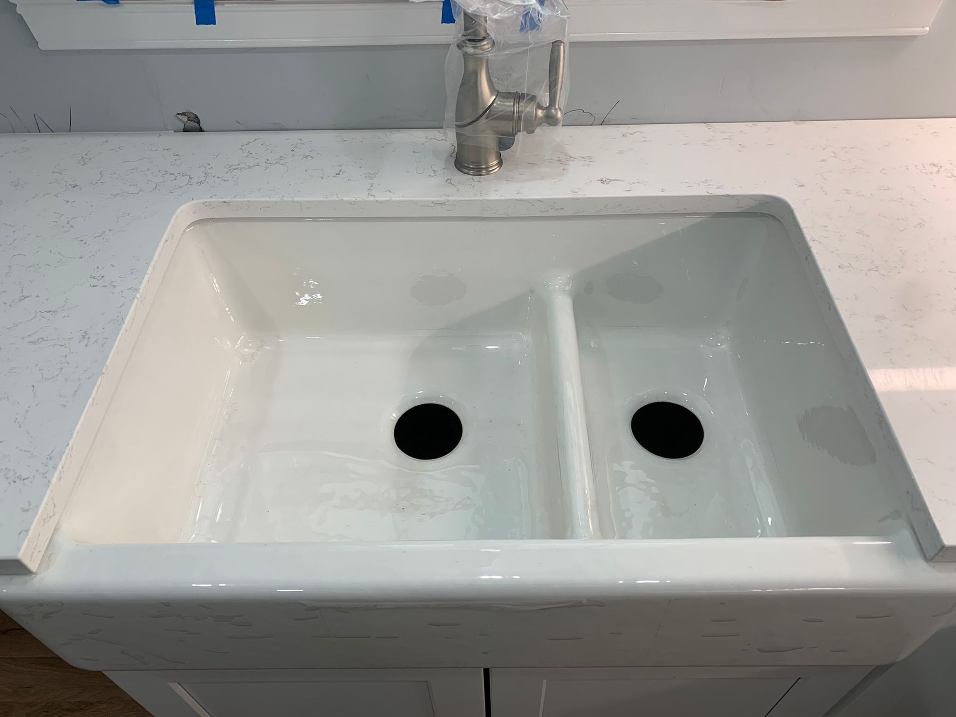 A white kitchen sink with two black holes in it is on a counter.