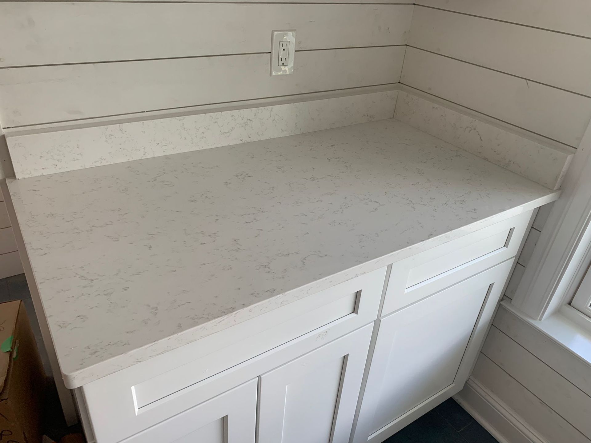 A kitchen counter with white cabinets and a white counter top.