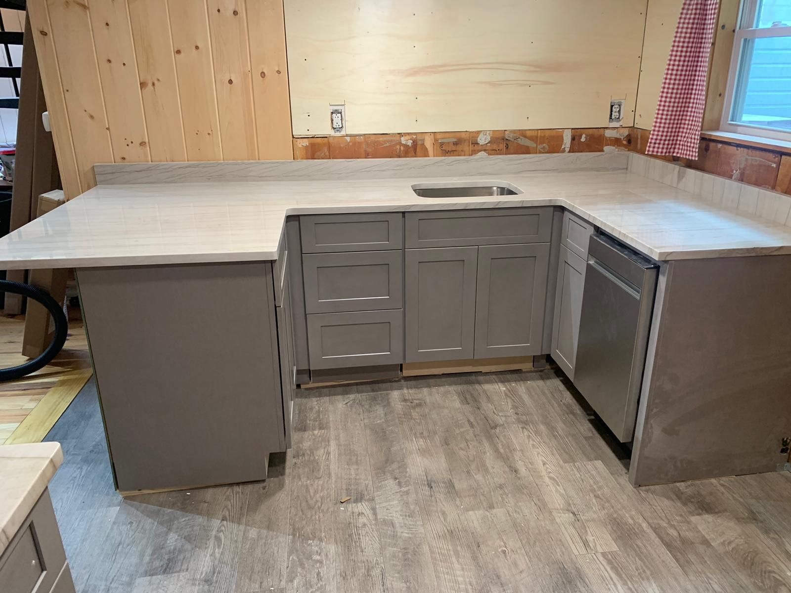 A kitchen with gray cabinets , a sink , and a dishwasher.