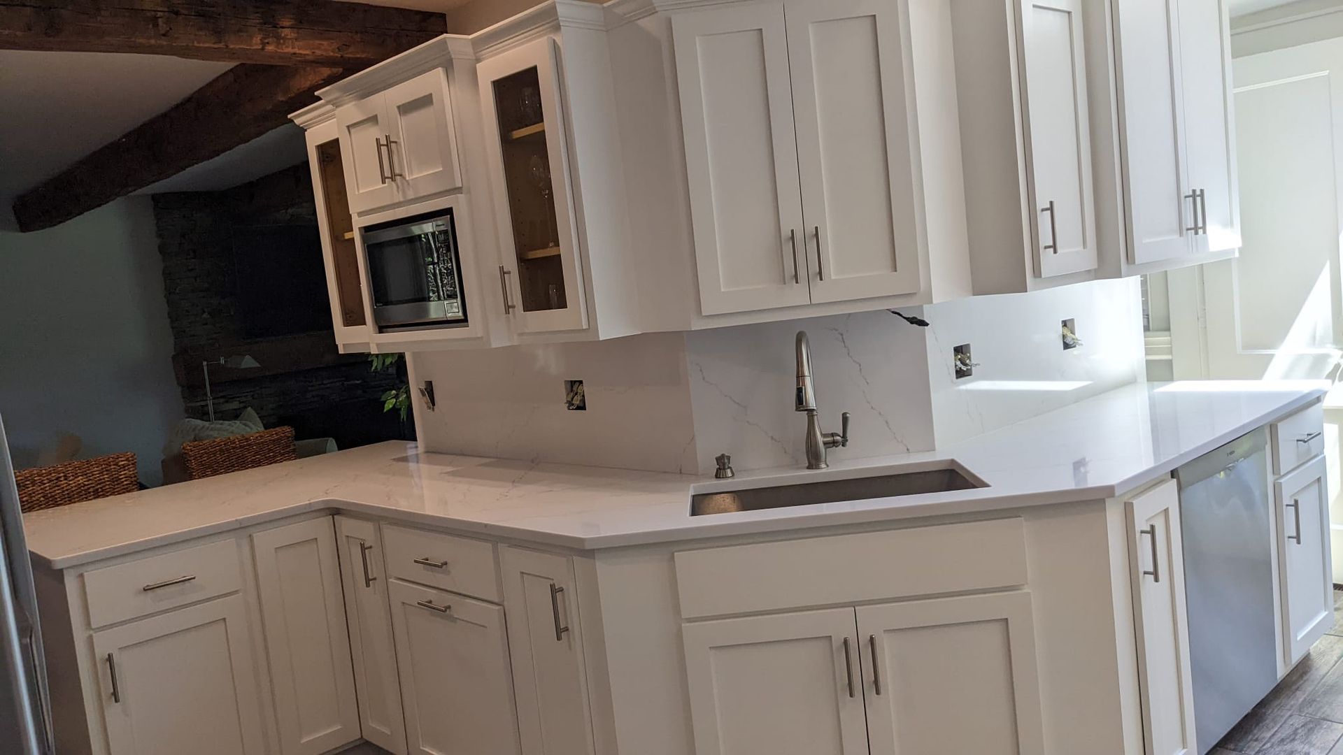 A kitchen with white cabinets , a sink , and a microwave.