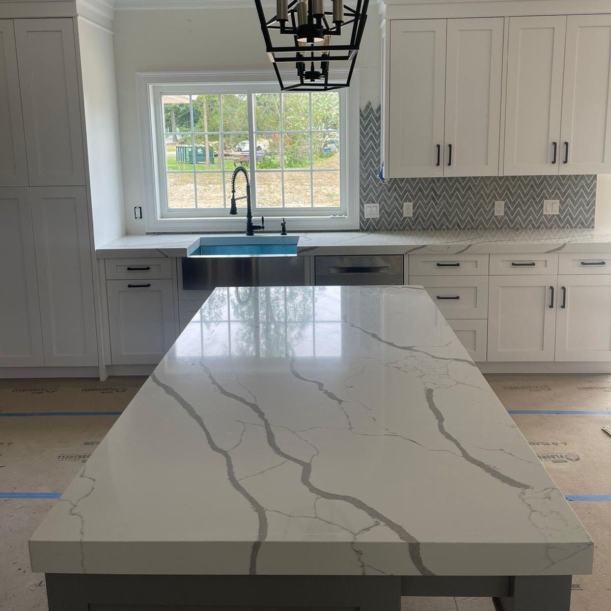 A kitchen with white cabinets and a marble counter top