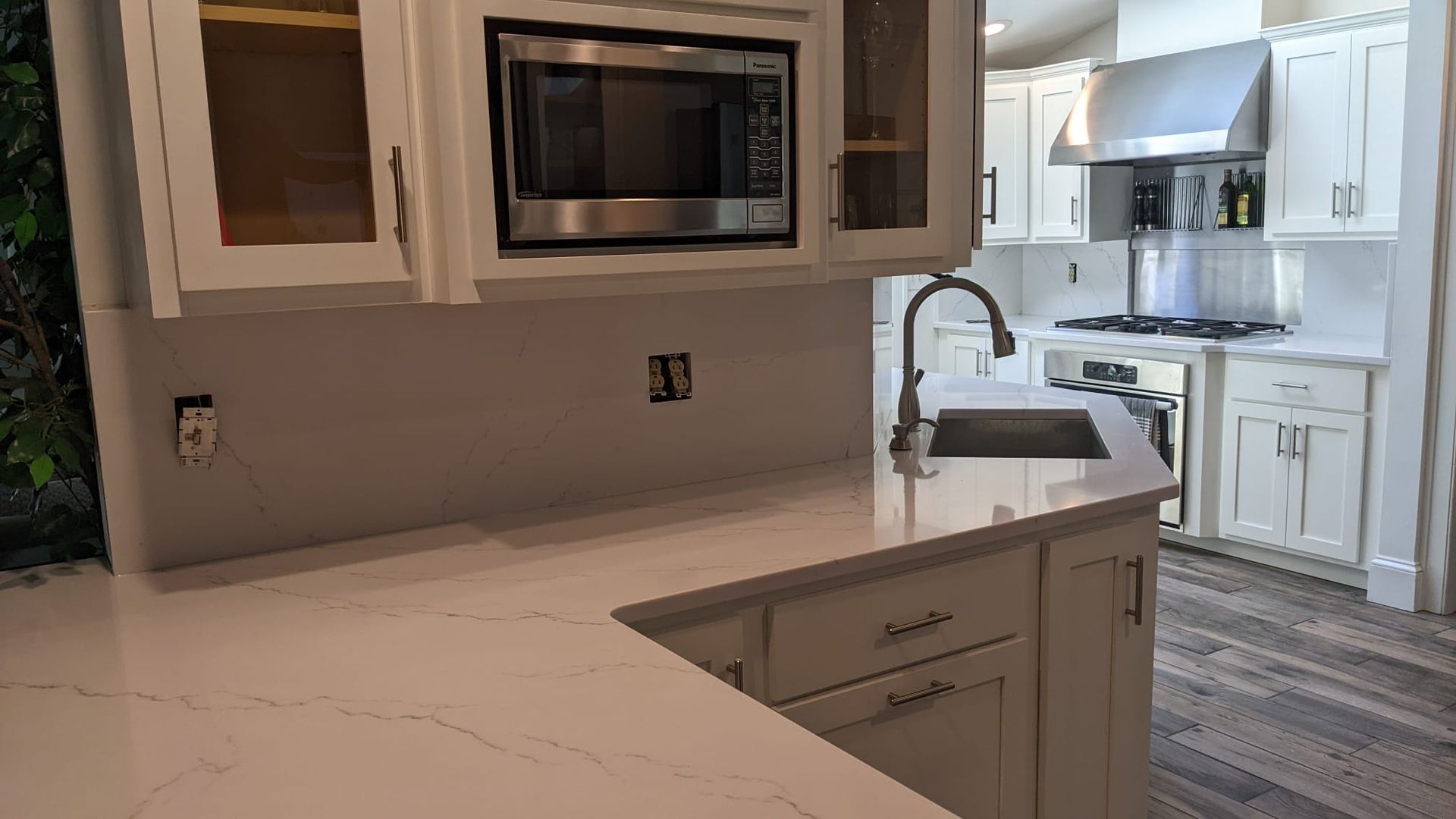 A kitchen with white cabinets , a sink , and a microwave.