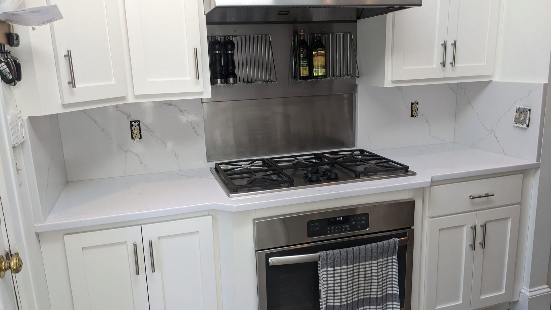 A kitchen with white cabinets , stainless steel appliances , and a stove top oven.