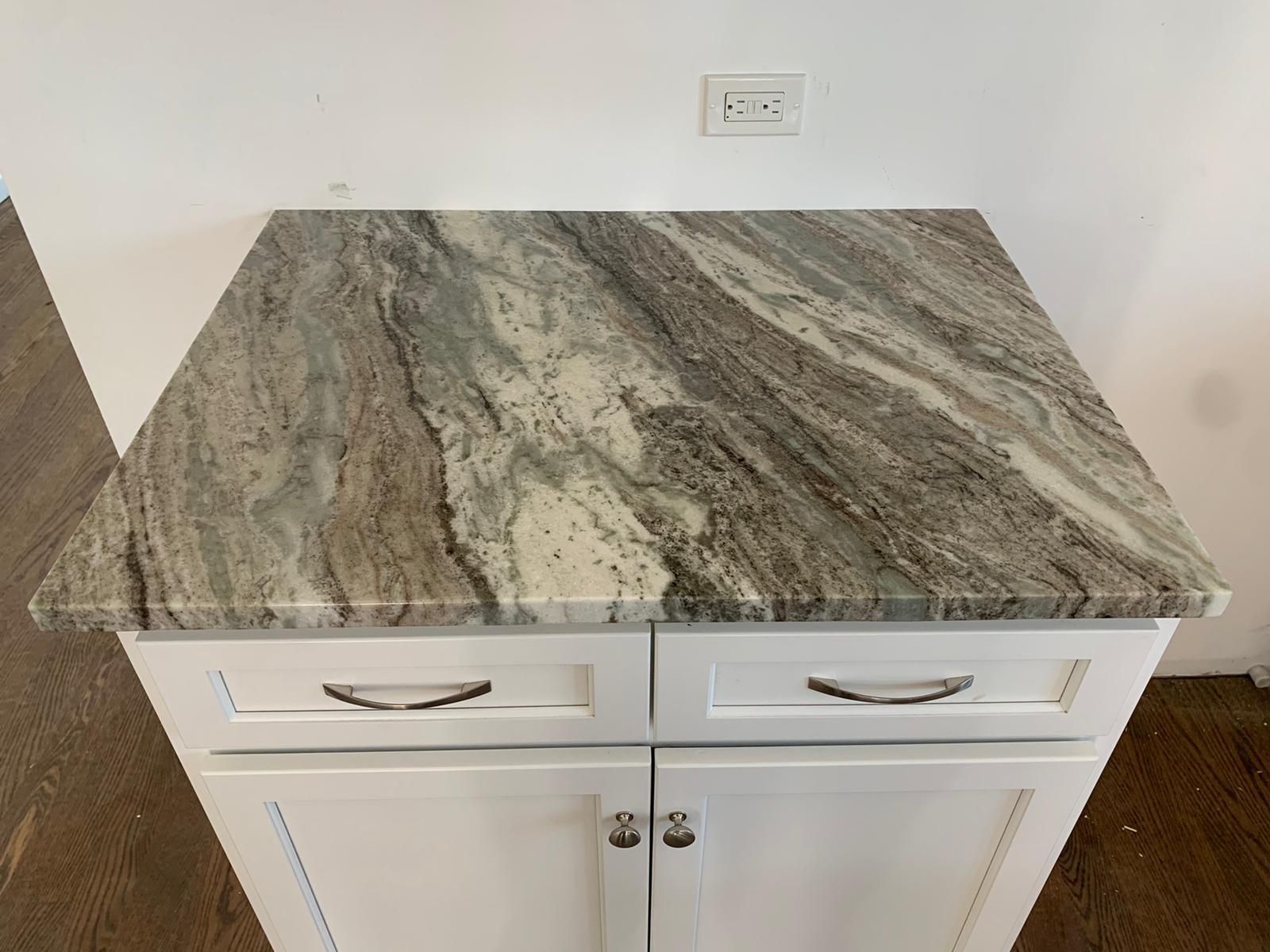 A white cabinet with a granite counter top in a kitchen.