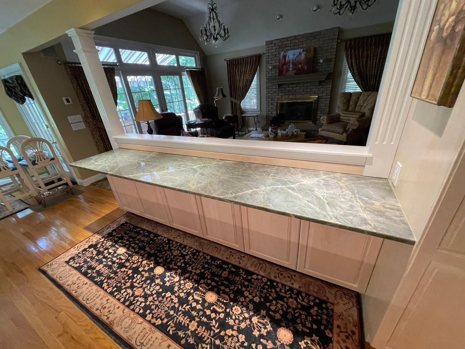 A kitchen with a marble counter top and a rug on the floor.