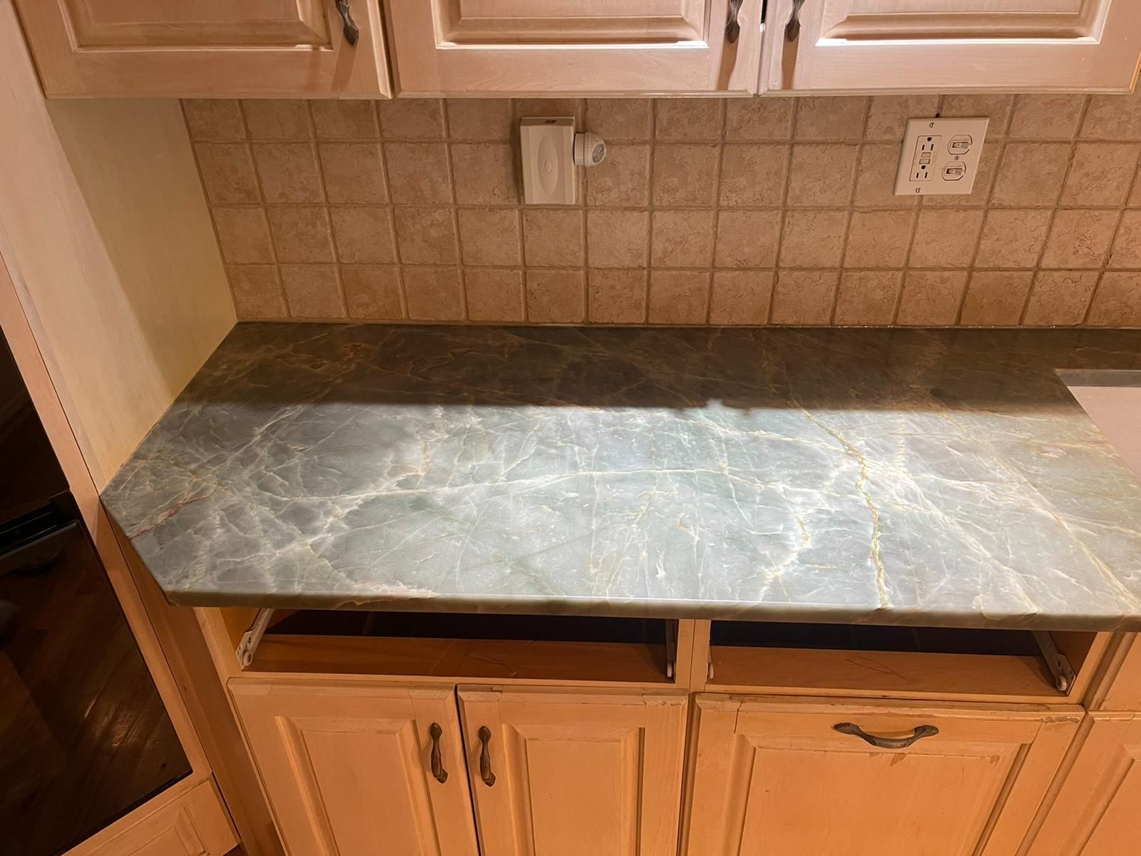 A kitchen counter with a marble counter top and white cabinets.