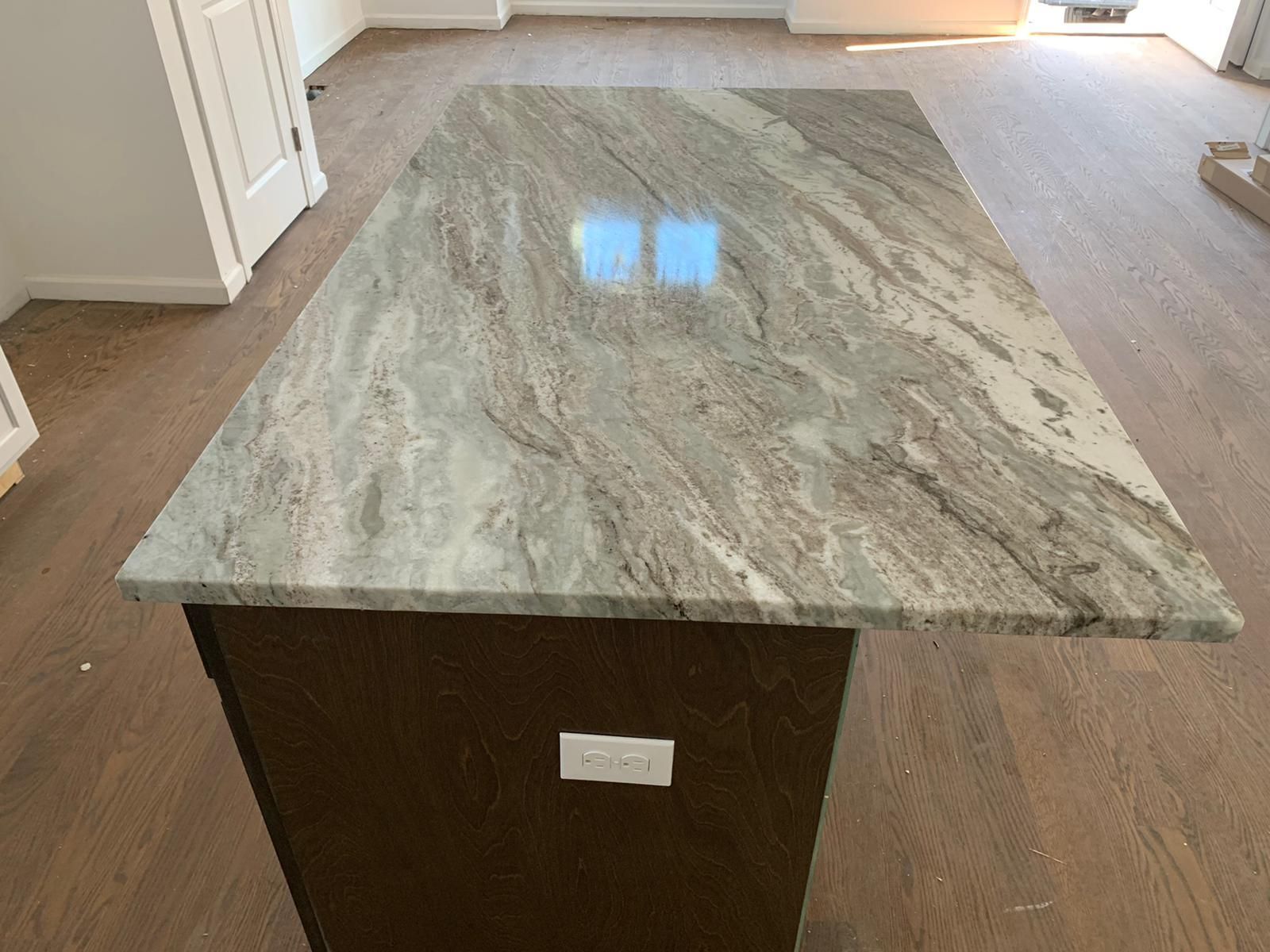 A kitchen island with a granite counter top and wooden cabinets.