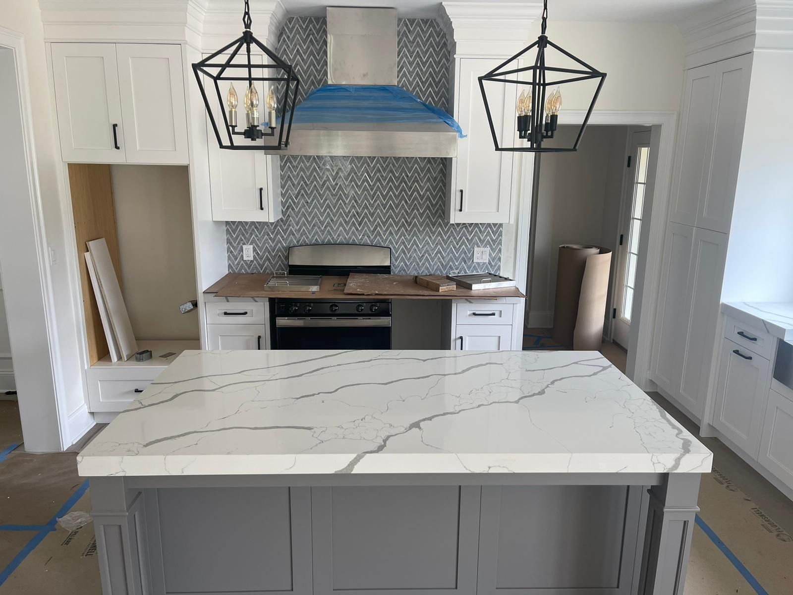 A kitchen with white cabinets and a large island in the middle.