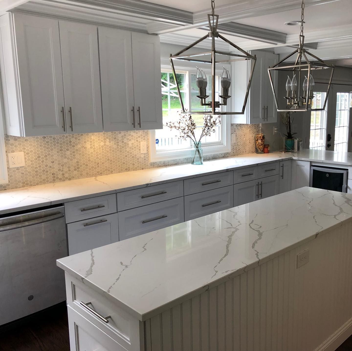 A kitchen with white cabinets , white counter tops , and a large island.