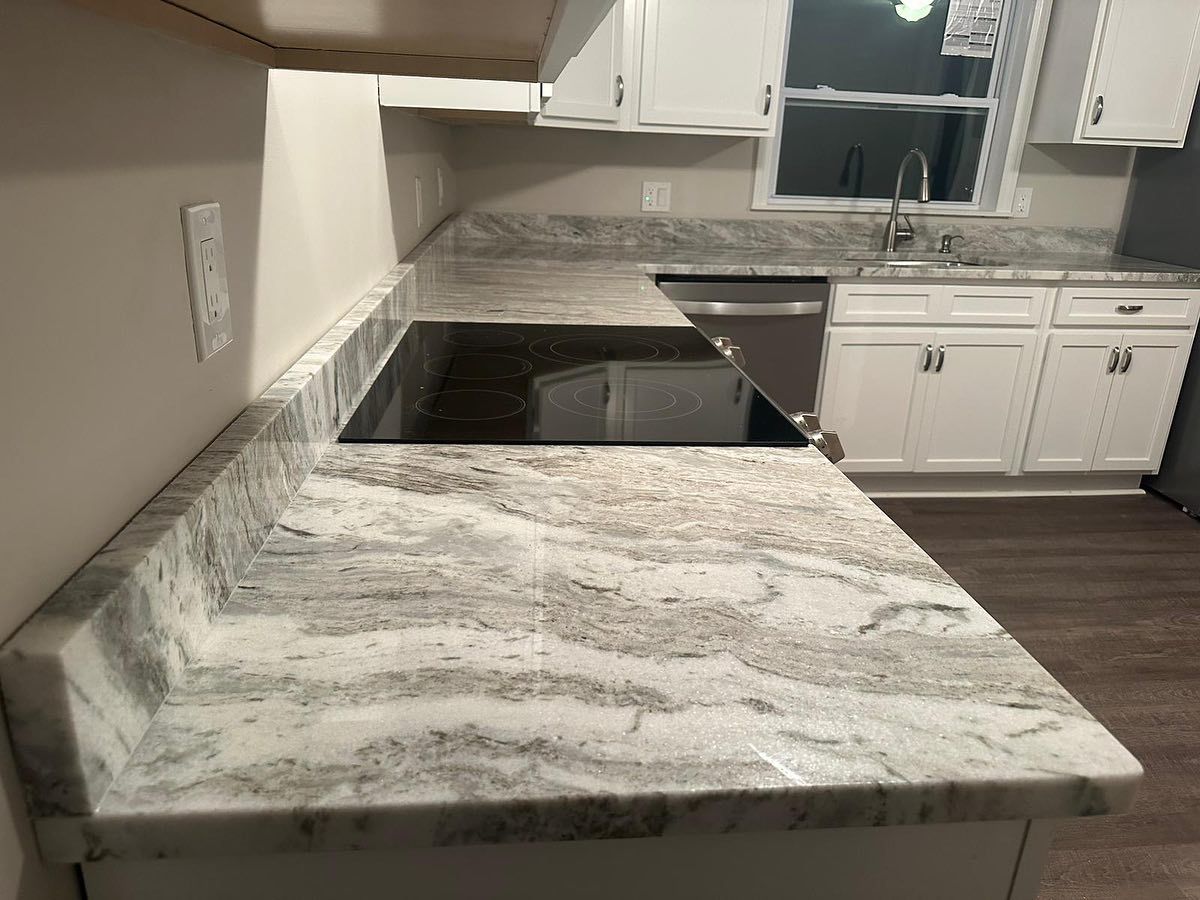 A kitchen with white cabinets and granite counter tops.