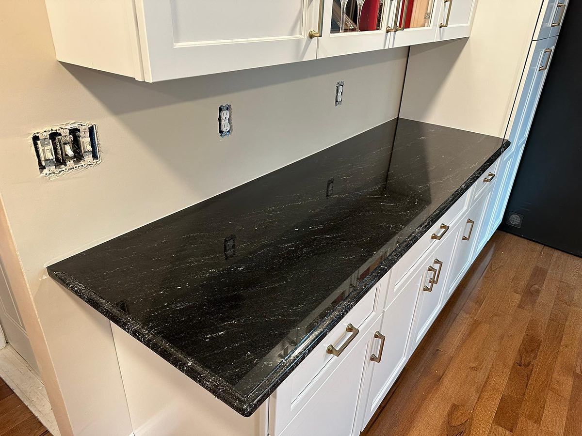 A kitchen with black granite counter tops and white cabinets.