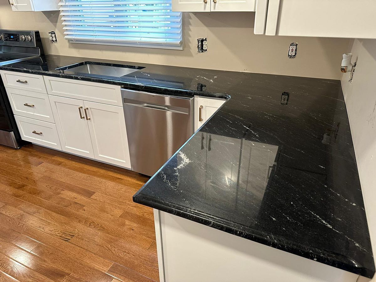 A kitchen with black granite counter tops and white cabinets