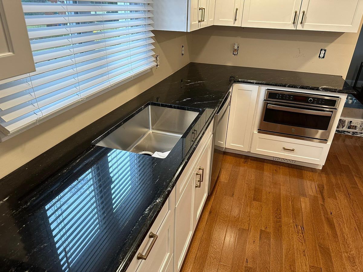 A kitchen with a sink and a window with blinds.