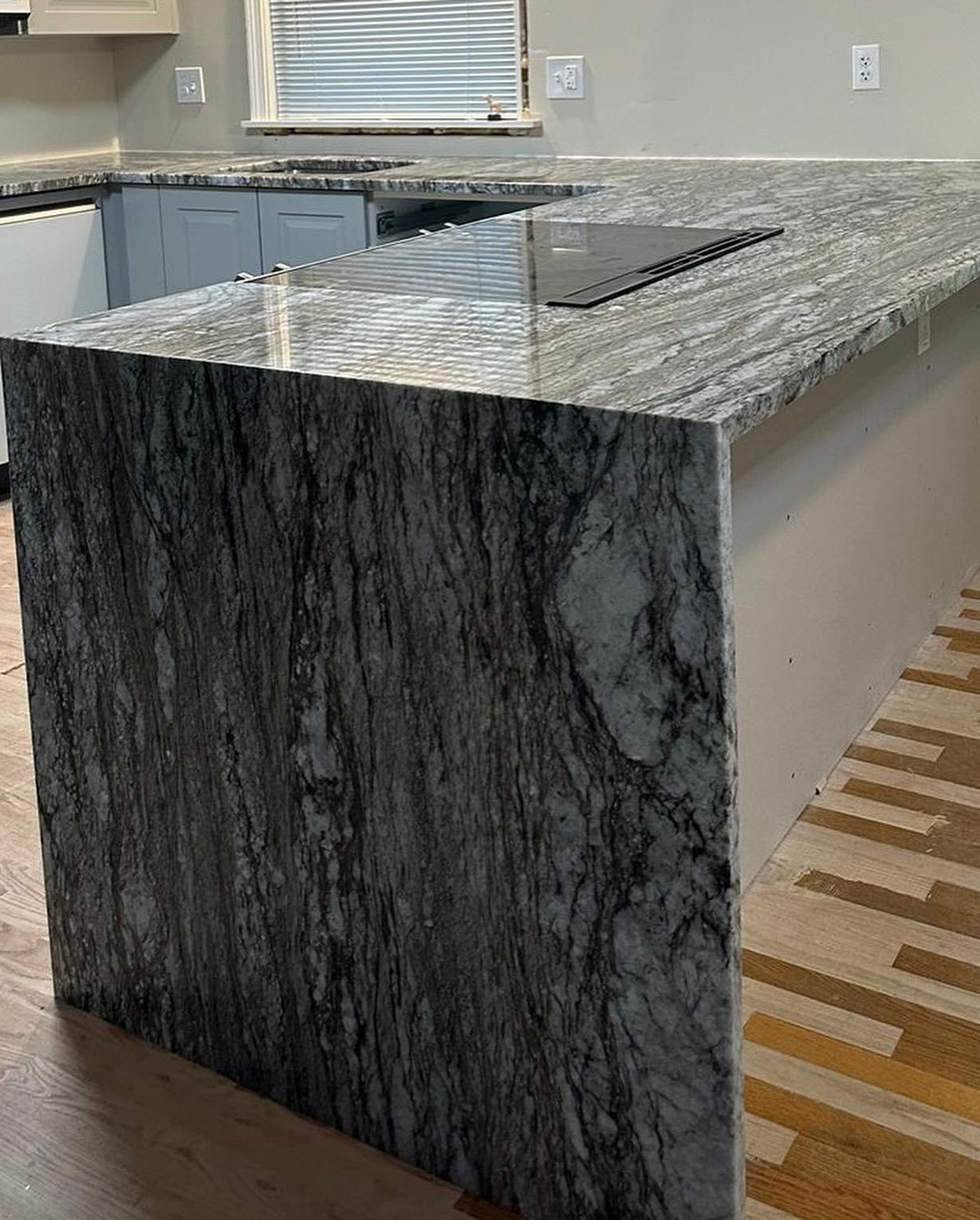 A kitchen with a large granite counter top and a stove top oven.