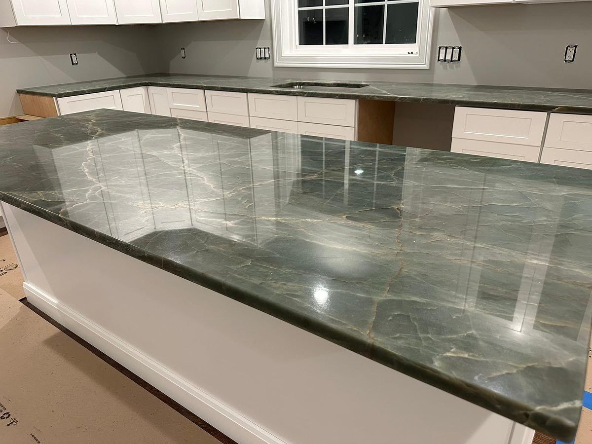 A kitchen with a green granite counter top and white cabinets.