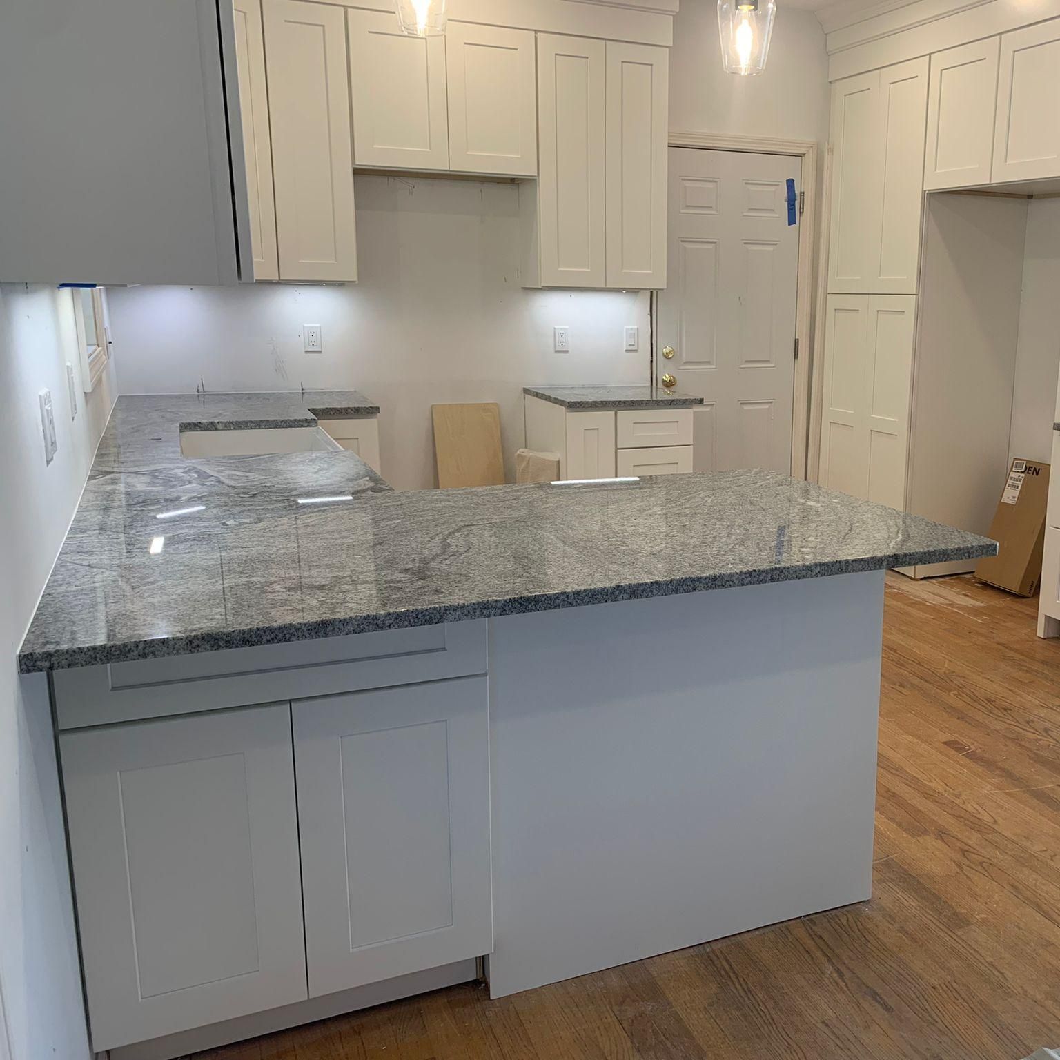 A kitchen with white cabinets and granite counter tops.