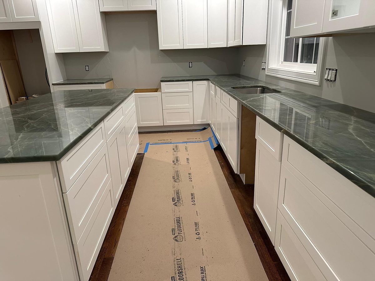 A kitchen with white cabinets and green granite counter tops.