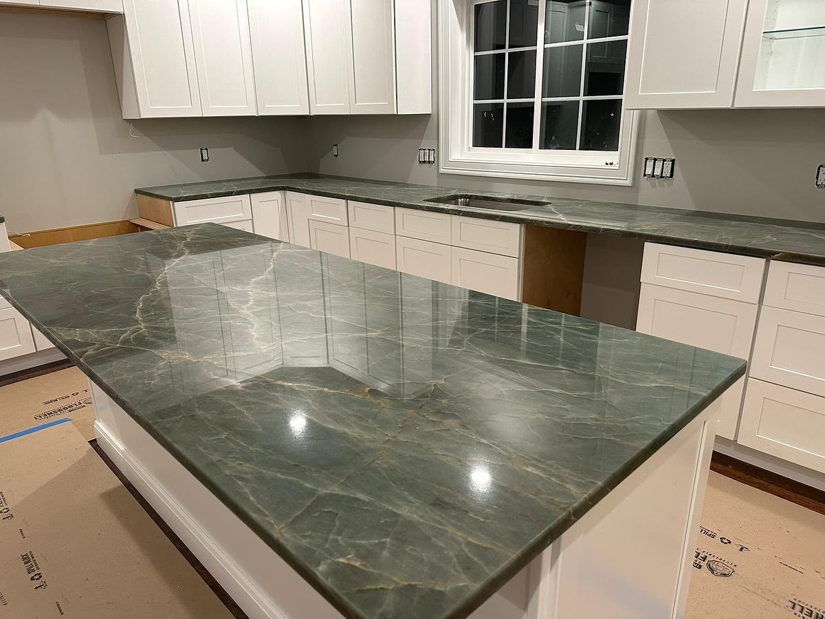 A kitchen with a green granite counter top and white cabinets.